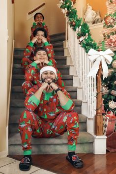 three people in matching christmas pajamas are sitting on the stairs with their hands over their mouths