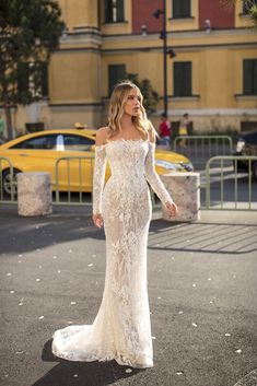 a woman in a white dress is walking down the street with her hand on her hip