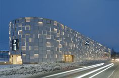 a large building that is next to a street with cars going by in the snow