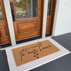 welcome to our home door mat with dog paw prints on the bottom and words that read,'welcome to our home '