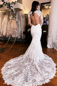 a woman in a white wedding dress looking at the back of her lace covered gown