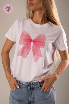 a woman wearing a t - shirt with a pink bow on it