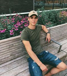 a young man sitting on top of a wooden bench