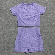 two pieces of clothing sitting on top of a gray surface, one in purple and the other in white