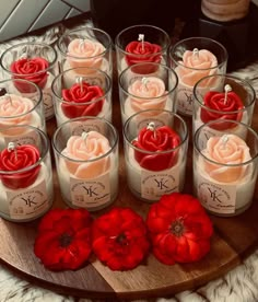 many candles are arranged on a wooden platter with red flowers in them and one candle is surrounded by smaller ones