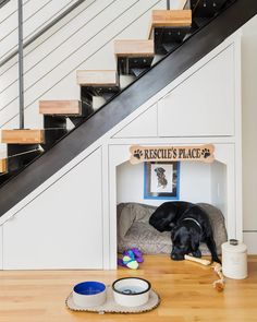 a dog laying on top of a couch under a stair case next to a set of stairs