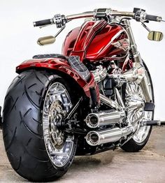 a red motorcycle parked on top of a parking lot next to a white wall in the background