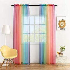 a room with a chair, window and rainbow curtains