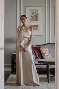 a woman is standing in a room wearing a dress with a bow on it's neck