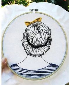 a woman's head with a bow in her hair is embroidered onto a white piece of fabric