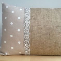 a pillow with white lace on it sitting on top of a wooden table next to a wall