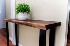 a potted plant sitting on top of a wooden table next to a white vase