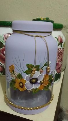 two vases with flowers painted on them sitting on a table next to each other