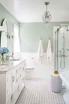 a bathroom with two sinks, a bathtub and a chandelier hanging from the ceiling