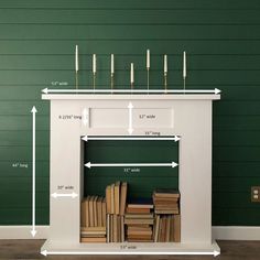 a white fireplace with candles and books on the mantel height is shown in front of a green wall