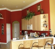 a woman sitting at a kitchen island in a red and yellow room with chairs around it