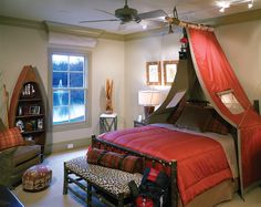 a bedroom with a canopy bed and leopard print pillows on the floor, in front of a window