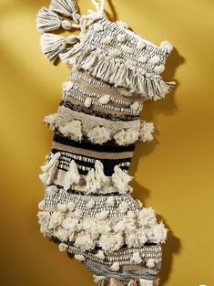 a stocking with tassels hanging from the side on a yellow wall in front of a gold background