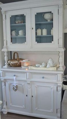 a white china cabinet with glass doors in a living room