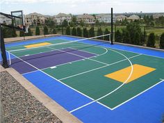 an outdoor basketball court in the middle of a residential area with lots of trees and houses behind it