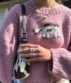 a woman wearing a pink sweater holding a cow print purse with her hand on the shoulder