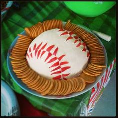 a cake decorated with a baseball and some crackers sitting on a table next to a box of chips