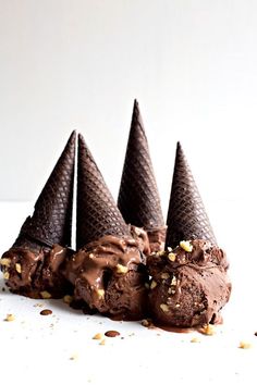 four ice cream cones with chocolate frosting and nuts