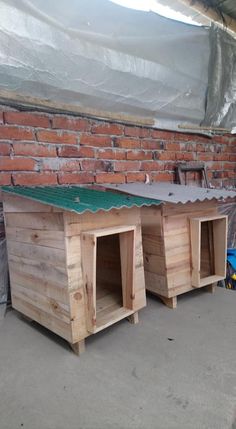 three wooden dog houses sitting in front of a brick wall