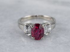 Always in style, rings such as this one can be worn as engagement rings, birthstone rings, or just for special occasions. We've set the center of this one with a high-quality, glowing red ruby. The side stones are bright white diamonds, reflecting plenty of light into the center stone. As an engagement ring will look well with a variety of bands, from a plain golden circle to a ruby and diamond eternity band. Metal: 14K White Gold Gem: Ruby 2.02 Carats Gem Measurements: 8.0 x 6.0 mm, Oval Accents: 8 Diamonds totaling .50 Carats, G in Color, SI1 in Clarity Ring Size: 6.75 Marks: “14K MFP” Stamped on the inside band Engagement Ring Modern, White Gold Ruby Ring, Rings Birthstone, Gold Ruby Ring, Gem Ruby, Ruby Ring Gold, Ruby And Diamond Ring, Ring Ruby, Gold Cocktail Ring