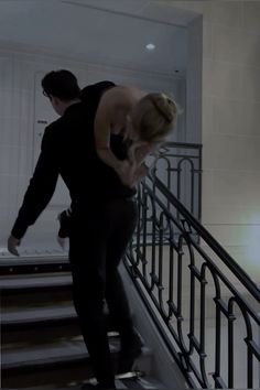 a man riding a skateboard down the side of a set of stairs next to a woman