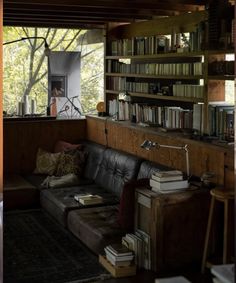 a living room filled with furniture and bookshelves next to a window covered in lots of books