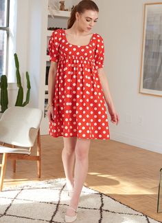 a woman in a red and white polka dot dress walking across a living room floor