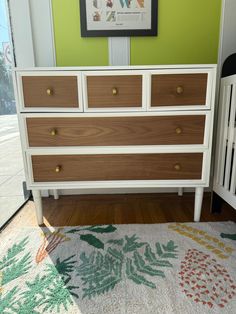 a baby crib in front of a green wall with a painting on the wall