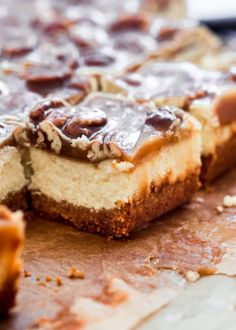 a piece of cheesecake with chocolate and nuts on it sitting on a cutting board