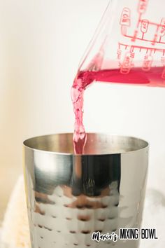 a person pouring red liquid into a metal cup