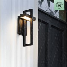 an outdoor wall light on the side of a building in the rain with snow falling