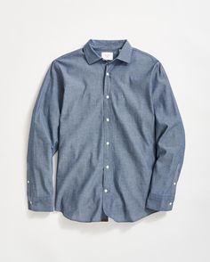 This shirt elevates the ultimate workwear fabric, hard-working chambray, in a proper dress shirt silhouette – offering the best of both worlds in one classic shirt. Constructed with a spread collar (with collar stays) and a pocketless front, it boasts a standard fit, a silhouette one inch longer than usual for the perfect tuck, and horizontal buttonholes to ensure things stay neat and buttoned. Thoughtful details include genuine mother-of-pearl buttons and gold thread stitched on the bottom buttonhole at the front placket - a distinguishing touch. It wears handsomely with a coat and tie, but looks smart dressed down with denim or chinos. This shirt is a standard fit. Washed Blue Chambray Collared Shirt, Affordable Chambray Button-up Tops, Blue Chambray Button-up Shirt, Washed Chambray Button-up Shirt, Medium Wash Chambray Button-up Blouse, Billy Reid, Fall Outerwear, Henley Sweater, Smart Dress