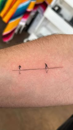 a person with a small tattoo on their arm that has two birds sitting on the line