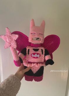 a person holding up a pink crocheted toy