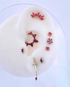 an assortment of jewelry is displayed on a white plate, including earrings and brooches