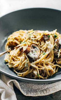 a plate of pasta with mushrooms and parmesan cheese on top, ready to be eaten