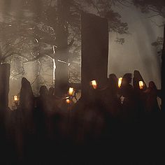 a group of people holding candles in front of a cross on a foggy day