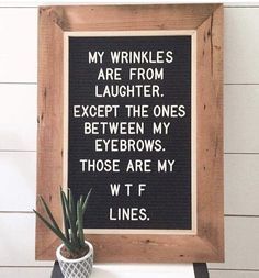 a wooden frame holding a sign that says, my wrinkles are from laughter except the ones between my eyebrows those are my wt f lines