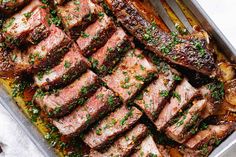 a pan filled with meat and vegetables on top of a table next to utensils