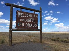 a welcome sign to colorful colorado in the middle of an open field with blue sky and clouds