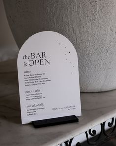 the bar is open sign sitting next to a potted plant on a marble table