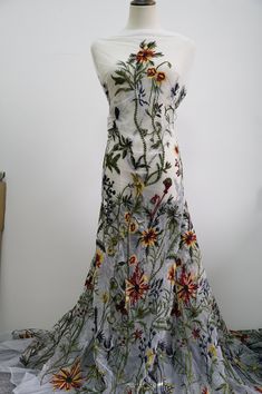 a dress with flowers on it sitting on a mannequin