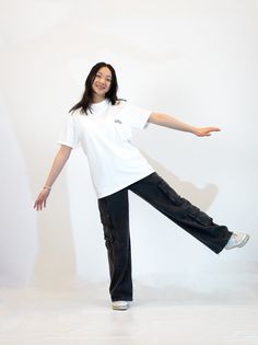 a woman in white shirt and black pants standing on one leg with her arms out