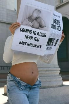 a pregnant woman holding up a sign with the words coming to a crib near you