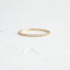 a thin gold band with small diamonds on it's sides, sitting on a white surface